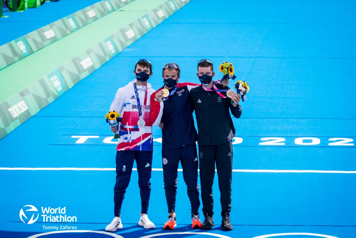 One for the history books. The three podium winners recieve their medals and grin (behind masks) for the camera. 