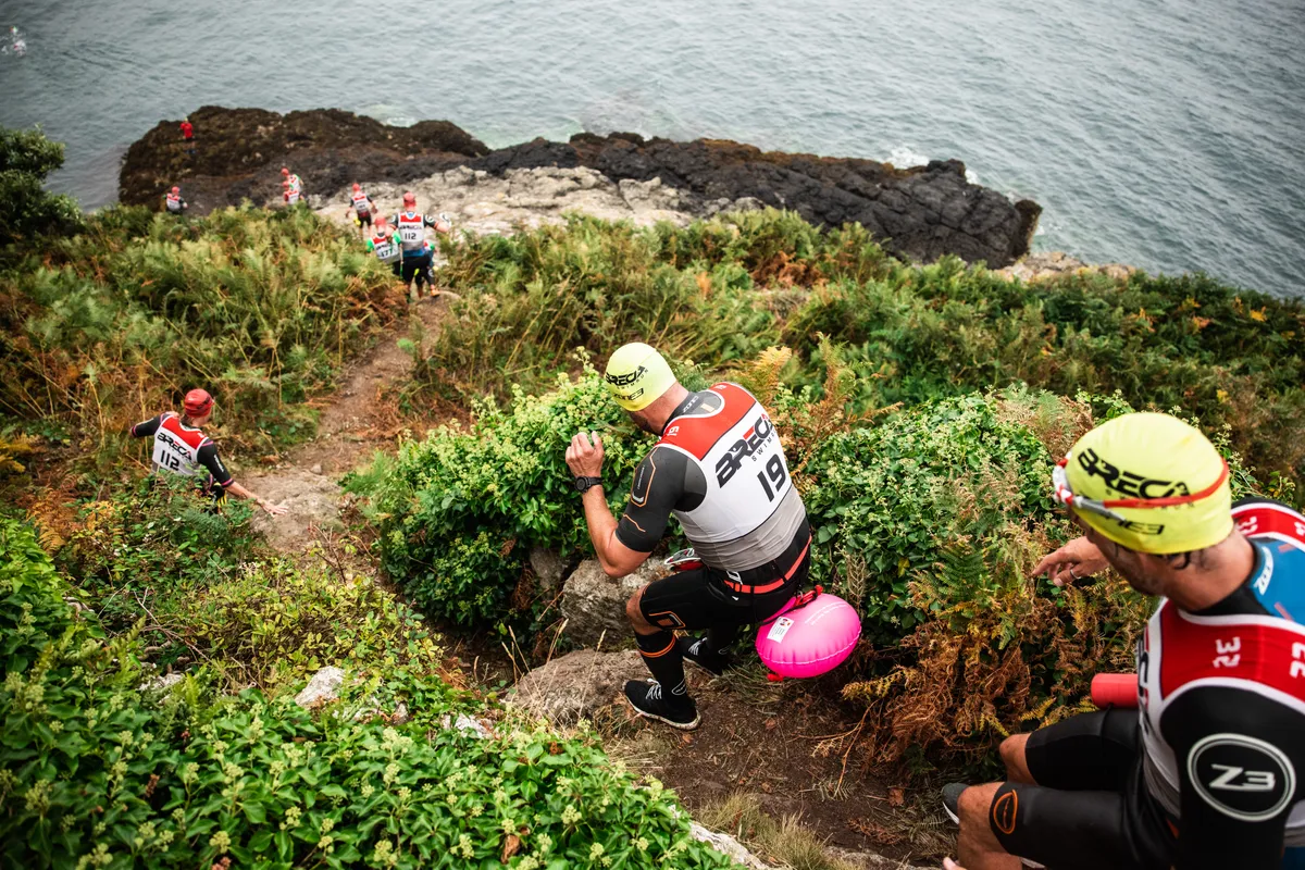 Swimrunners clamber down rocks and mud to reach the swim entrance / Andy Le Gresley Photography for Breca