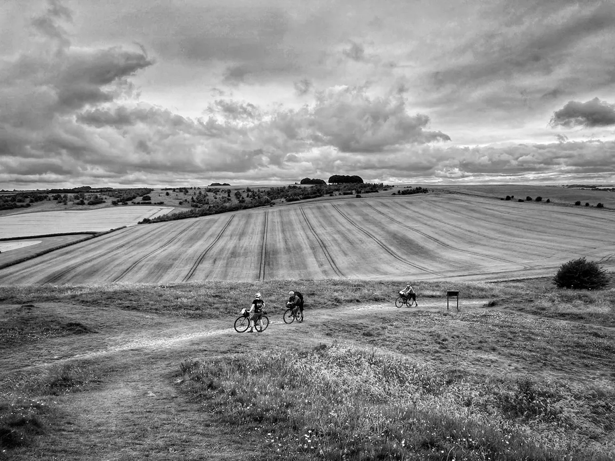 Three cyclists take a breather at the top of Barbury Castle, the Ridgeway.