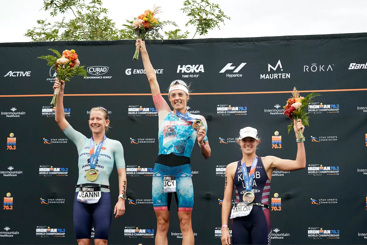 Taylor Knibb stands on the podium of the Ironman 70.3 World Championship
