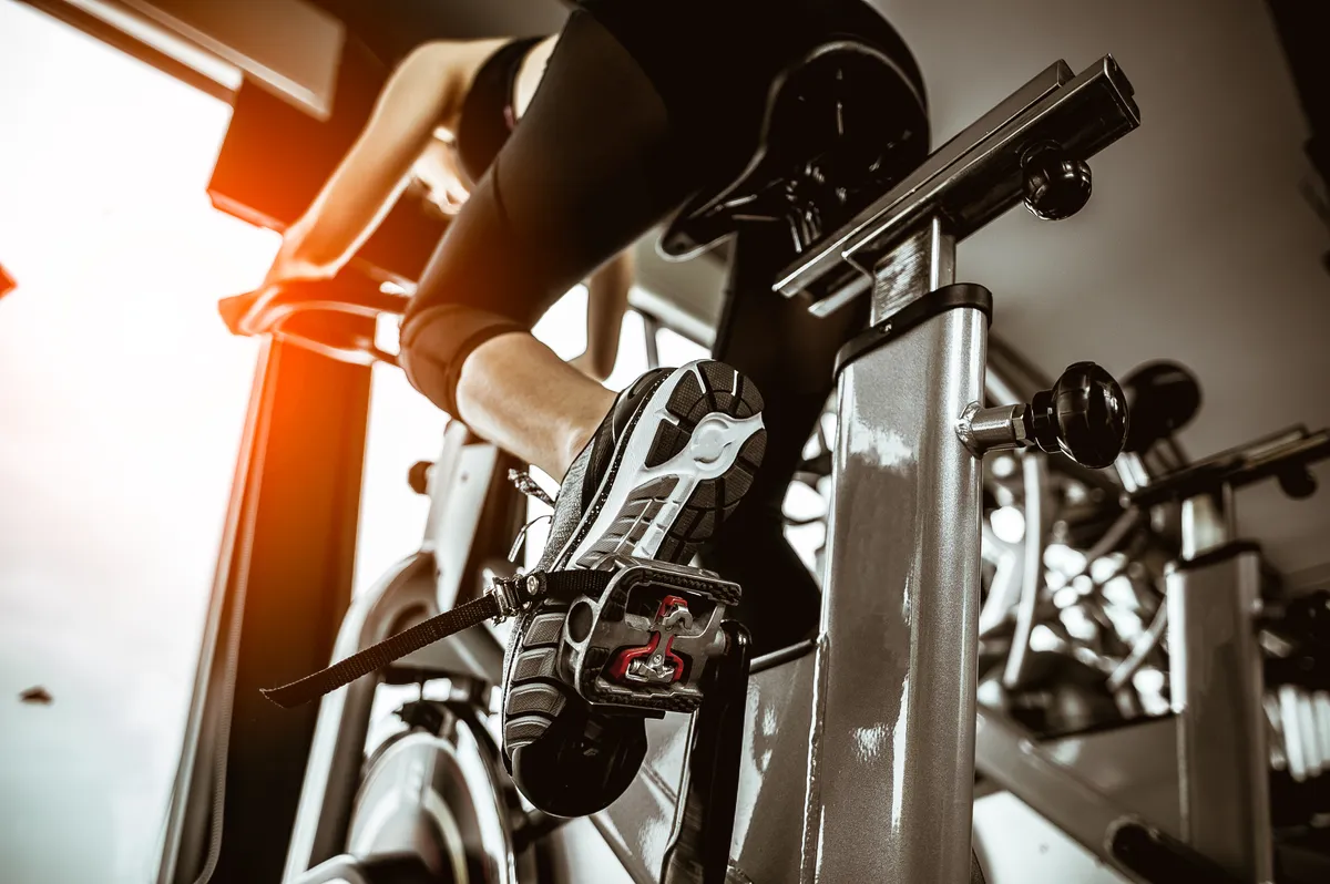 Low Angle View Of Woman Exercising On Bike In Gym