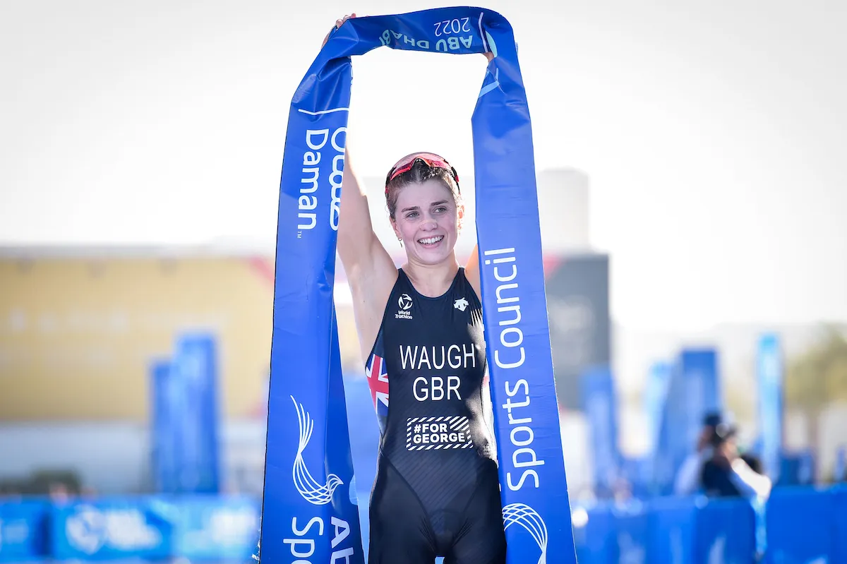 Kate Waugh lifting the winner's banner above her head having just crossed the line to become the 2022 World U23 Champion