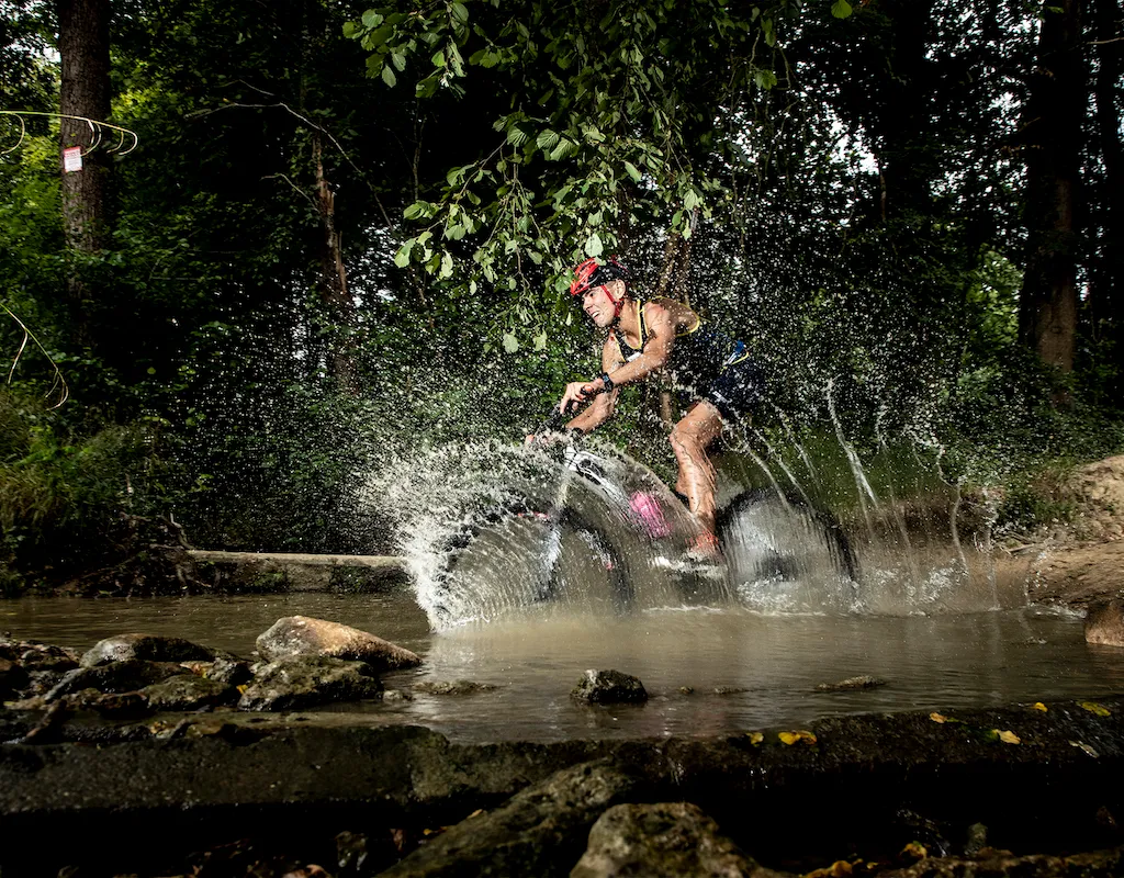 Male athlete cycling through water during an Xterra race
