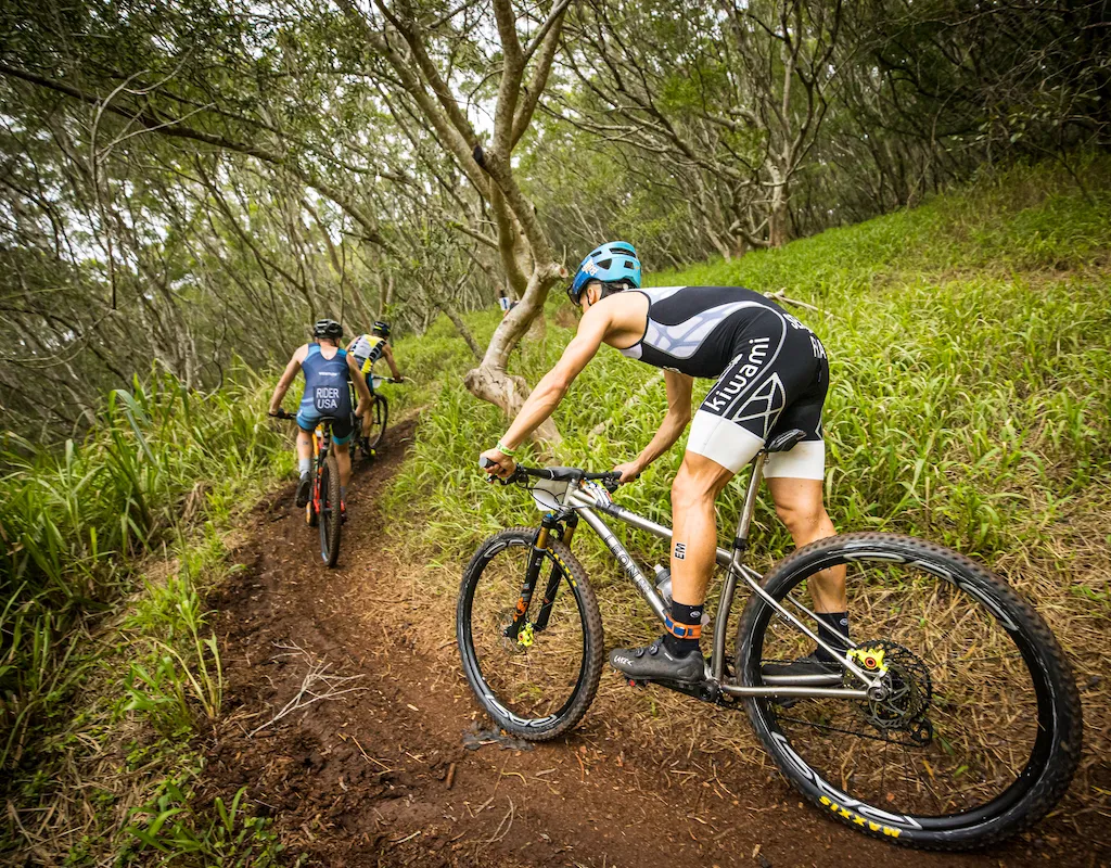 Three male cyclists cycling through wooded area on mountain bikes for an Xterra race