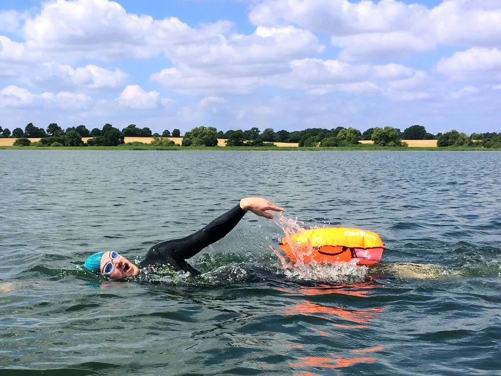 Person swimming in the sea wearing a wetsuit and cap