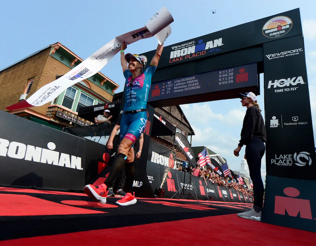 Lisa Norden celebrates as she crosses the finish line to win the 2021 Ironman Lake Placid