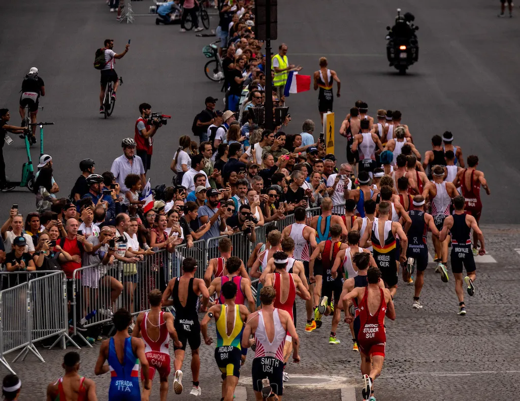 The pro men run past huge crowds along the cobbled streets of Paris at the Paris Olympics triathlon test event in 2023 