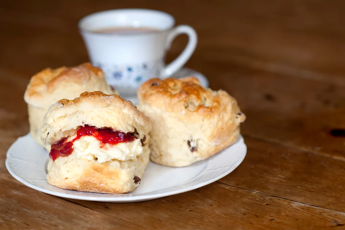 Delicious scones, cream and jam on a wooden table