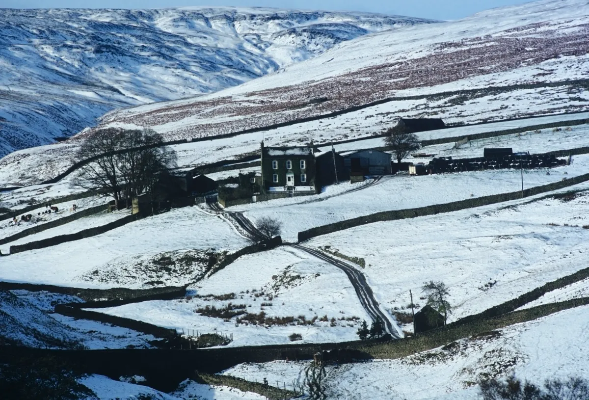 a remote farmhouse in the middle of snow covered fields in the winter - yorkshire dales national park, arkengarthdale, uk