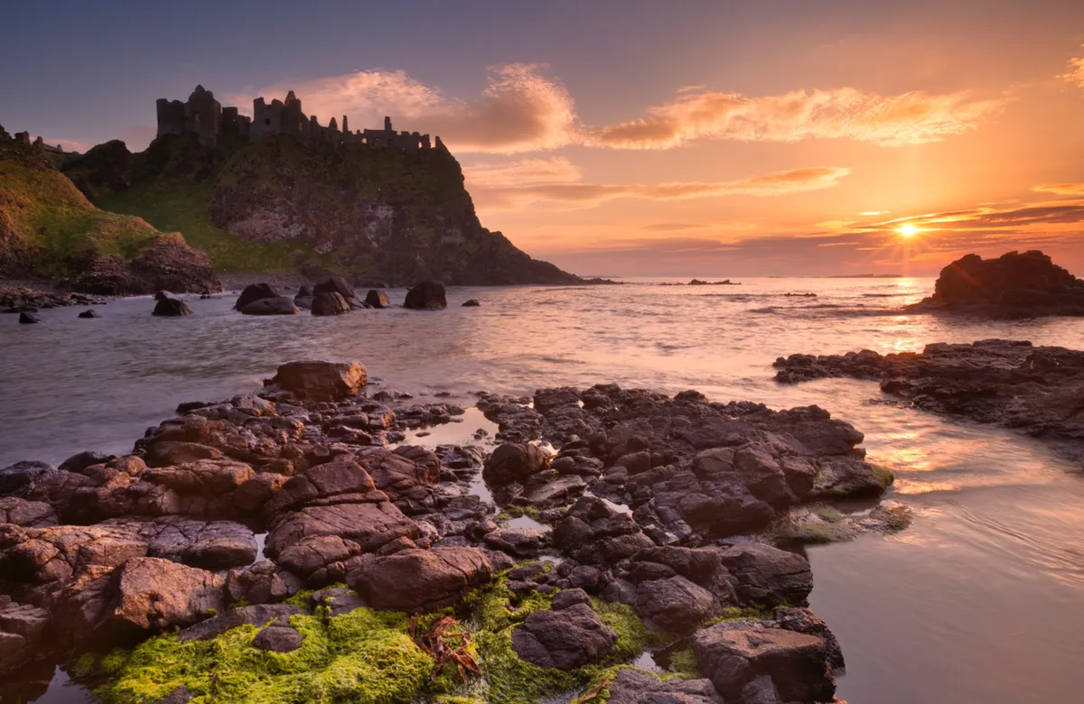 Duncluce Castle at sunset with sea and cliffs
