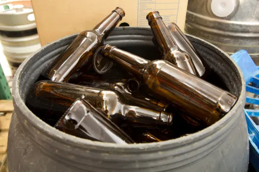 A barrel full of empty glass bottles in a brewery