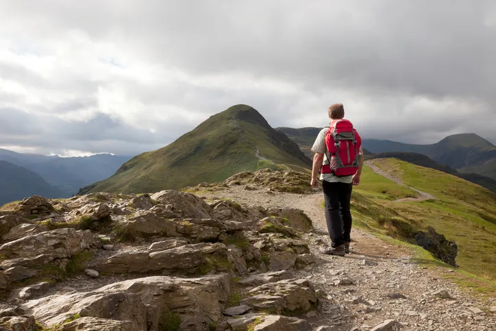 A male hiker admires the view from the top of Catbells in the Lake District National Park, Cumbria, England.