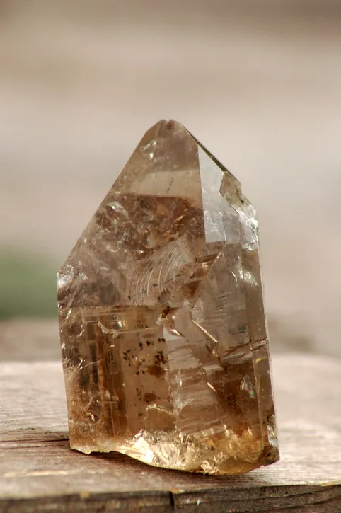 Rough natural smokey quartz crystal with dark inclusions