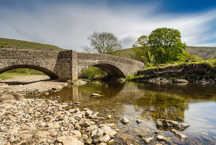 The bridge over the river at Buckden, North Yorkshire in the Yorkshire Dales. Long exposure shot to give some cloud blur, and reflections in the water.