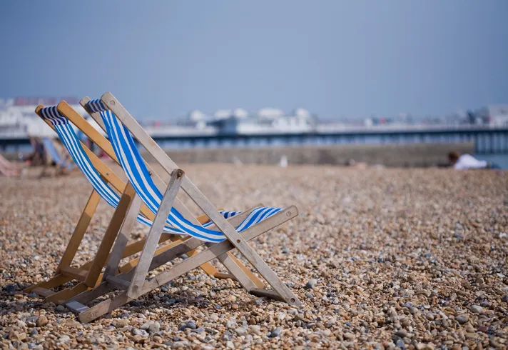Two blue and white deckchairs on Brighton pebble beach, UK