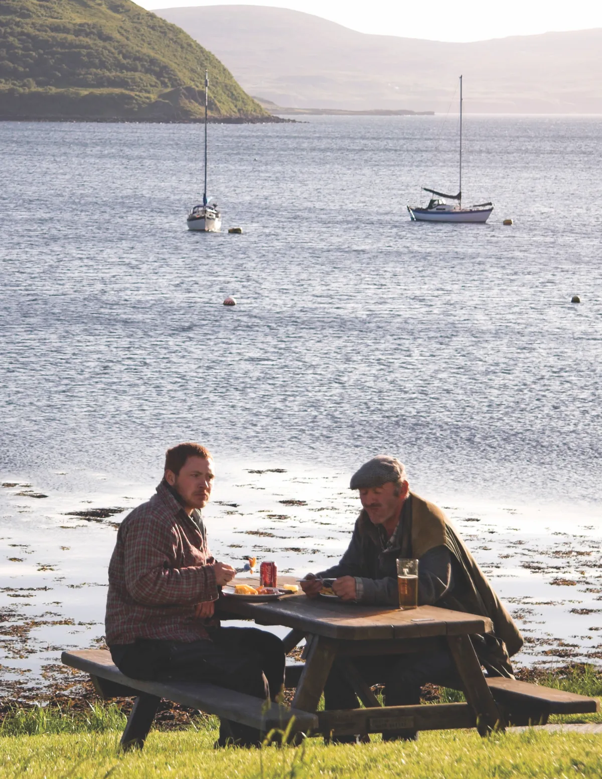 BC2A3R Two men drinking at a picnic table, Stein, Isle of Skye, Inner Hebrides, West Coast of Scotland, UK. Image shot 2009. Exact date unknown.