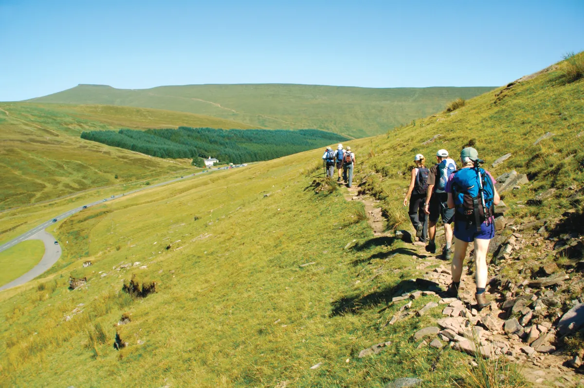 Guided walking group on hillside track heading toward Storey Arms in the Brecon Beacons National Park ©Getty