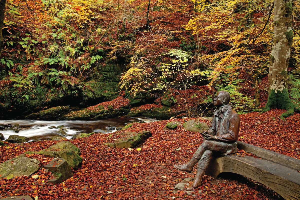Bench with a seated stature beside a small fast flowing river
