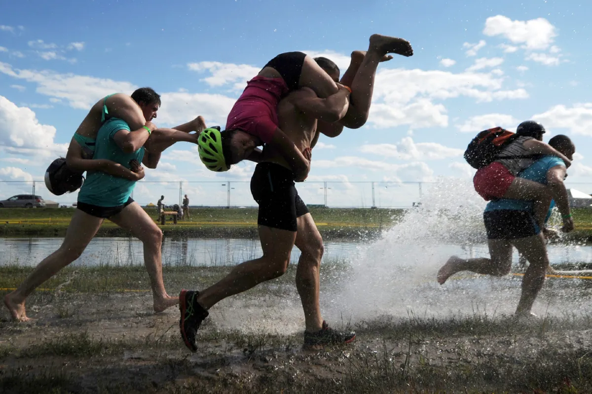 Man running carrying a women during the annual 'wife carrying championshios'