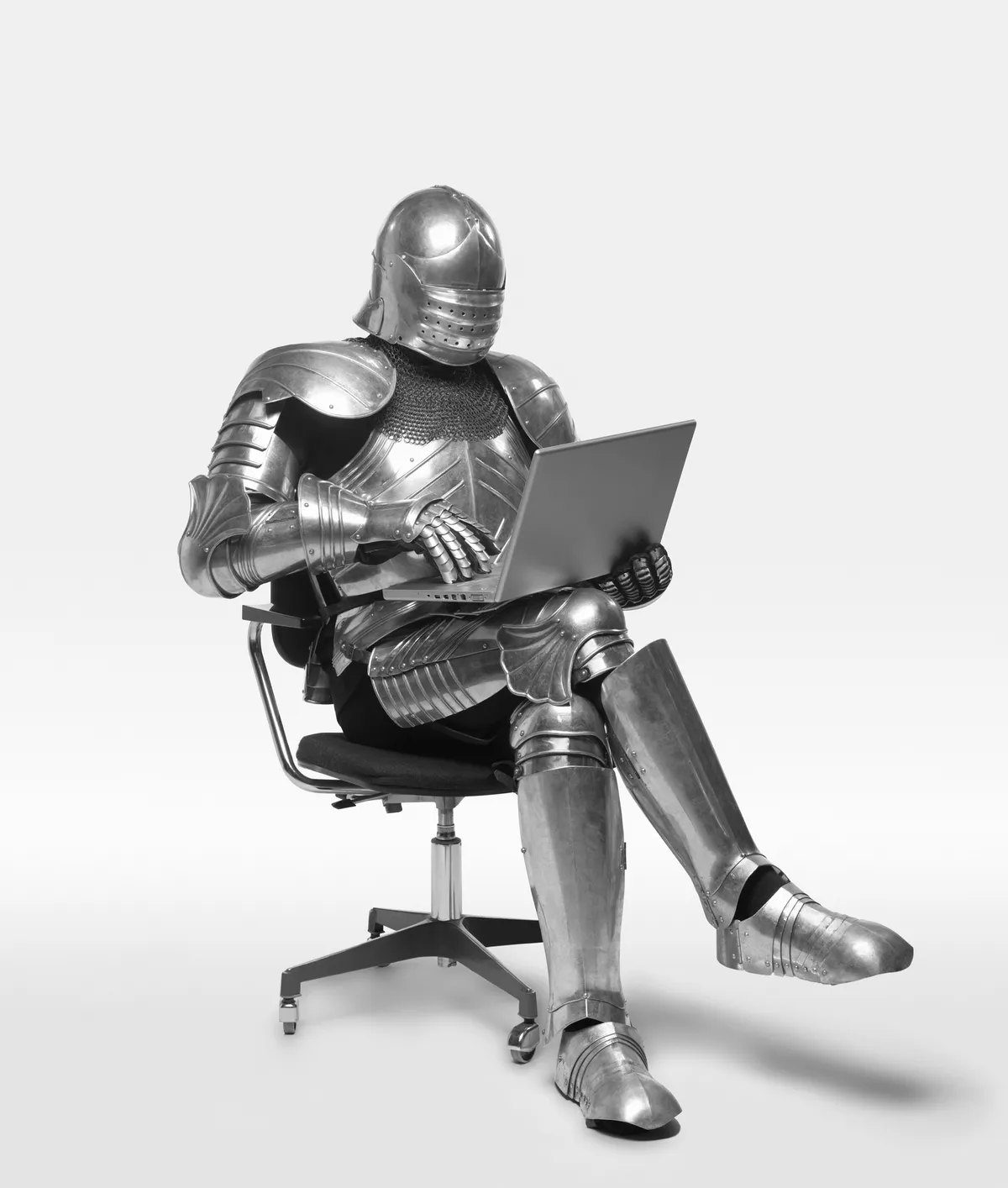 A person using a laptop while wearing a suit of armour
