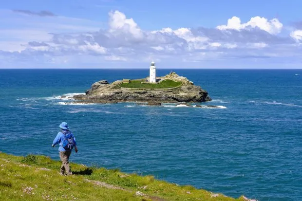 Woman hikes on coastal route at Godrevy Point, Godrevy Lighthouse on Godrevy Island, near Gwithian, Cornwall, England, Great Britain
