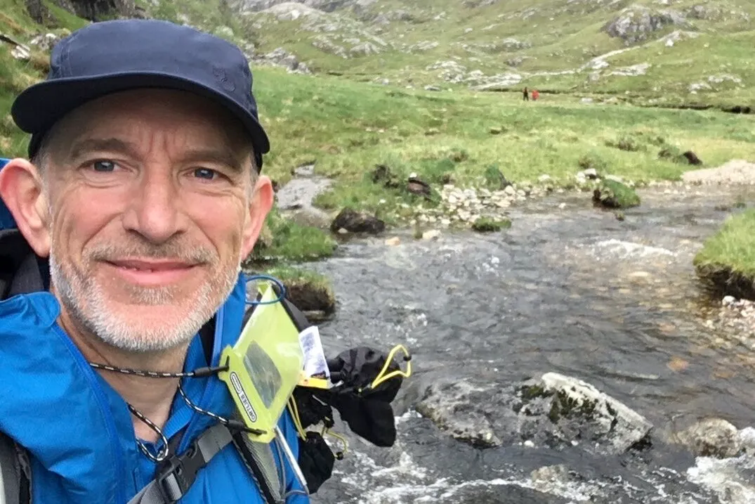 Joe Pontin wearing a cap, by a rushing river in the background.
