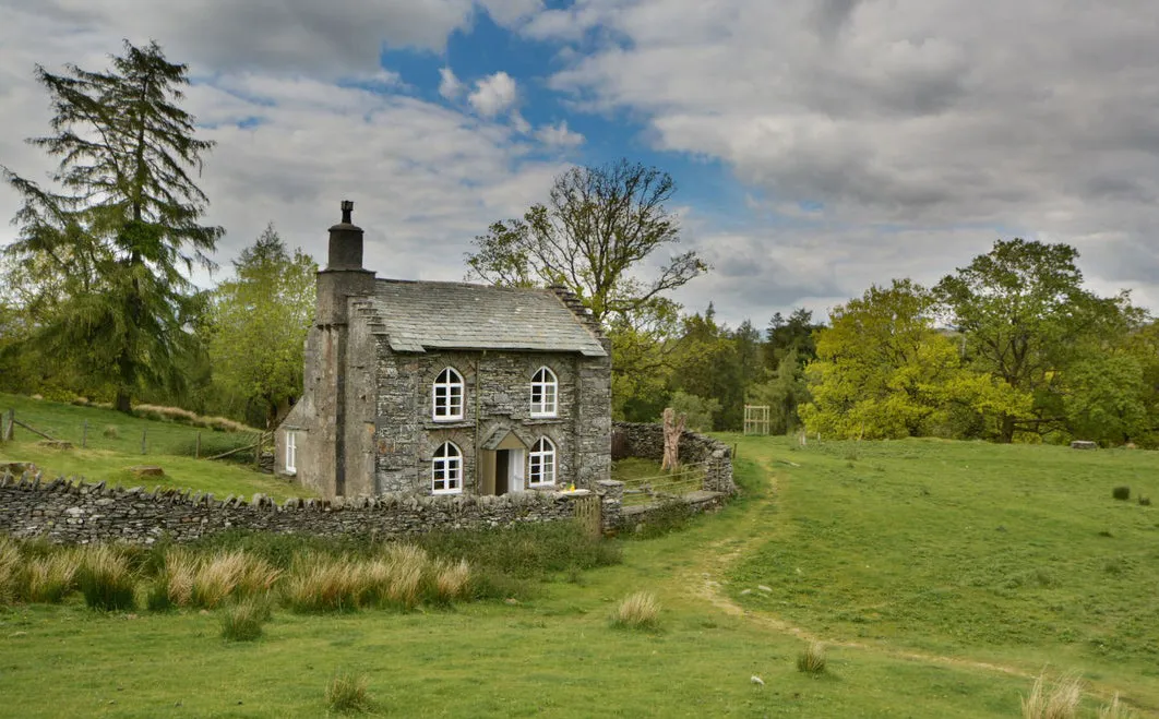 A stone cottage in a grassy landscape.