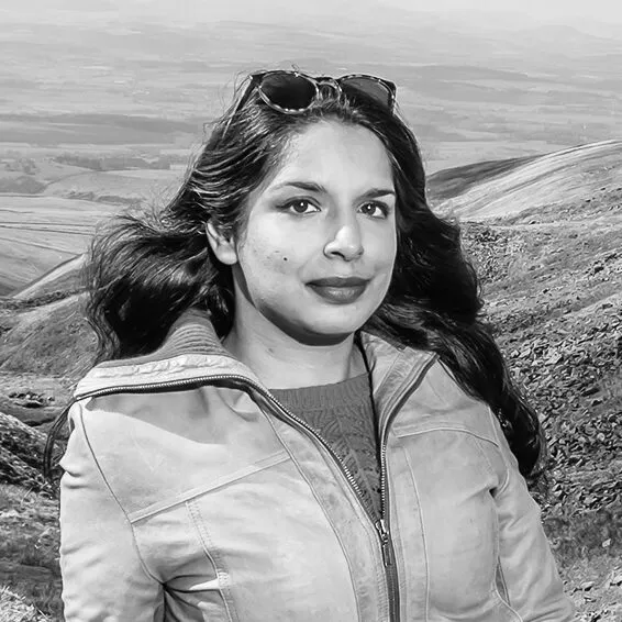 Black and white image of Anita Sethi, with mountains in background