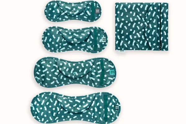 Set of four green cloth sanitary pads with white markings