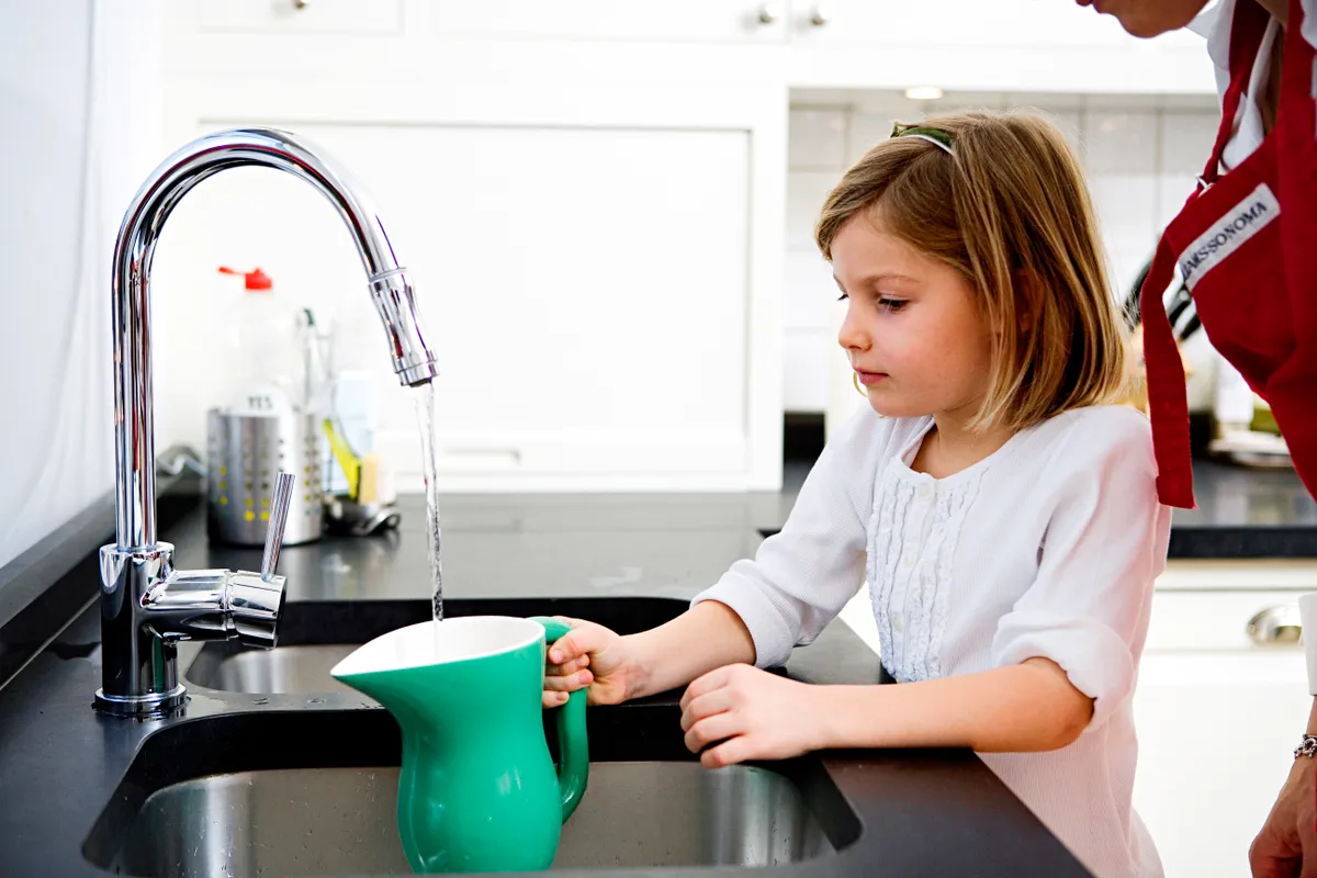 A girl filling a pitcher with water