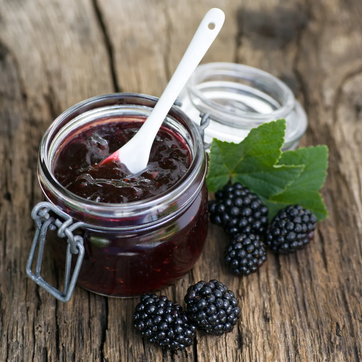 A kilner-type jar of blackberry jam with a spoon in it
