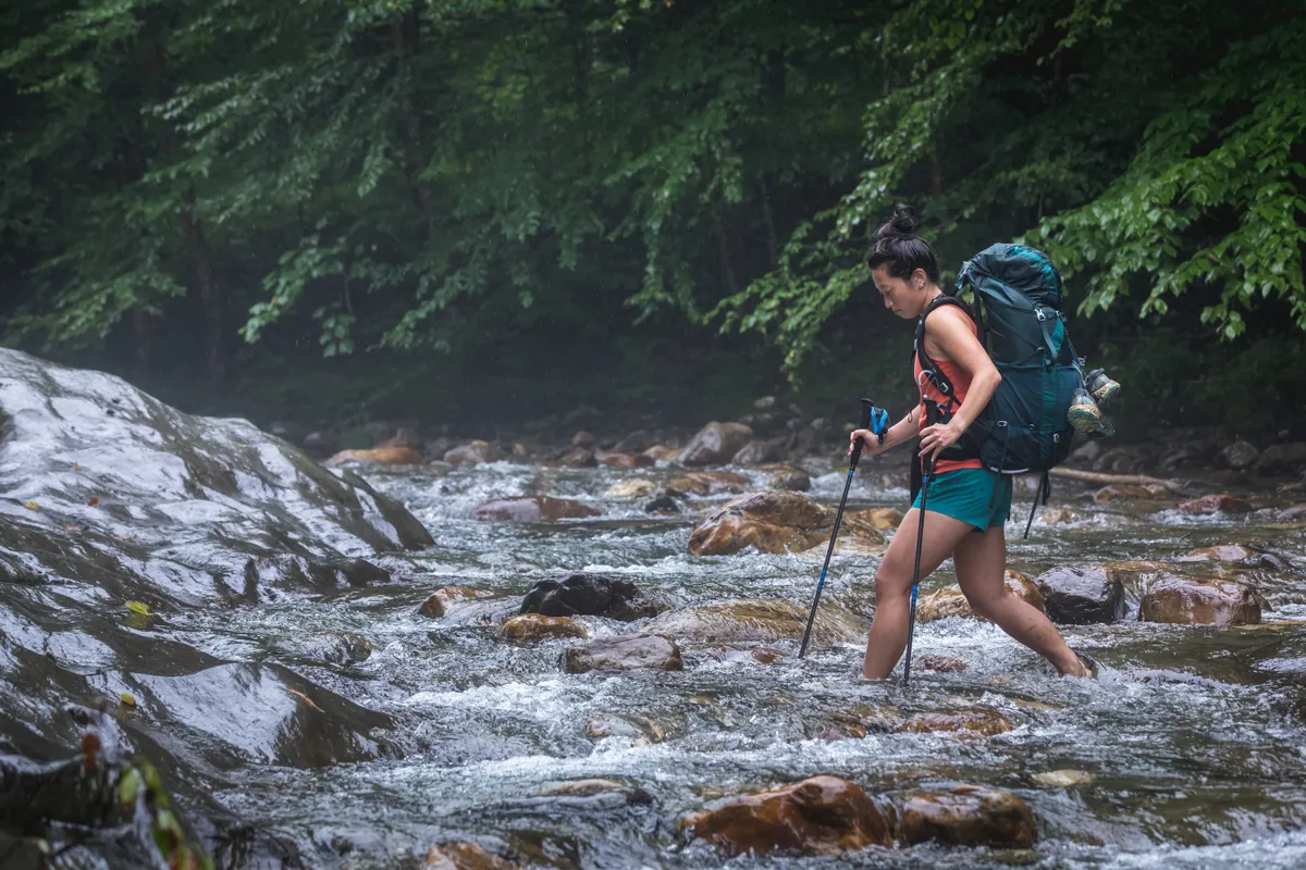 Women crossing a river with an Osprey Eja backpack