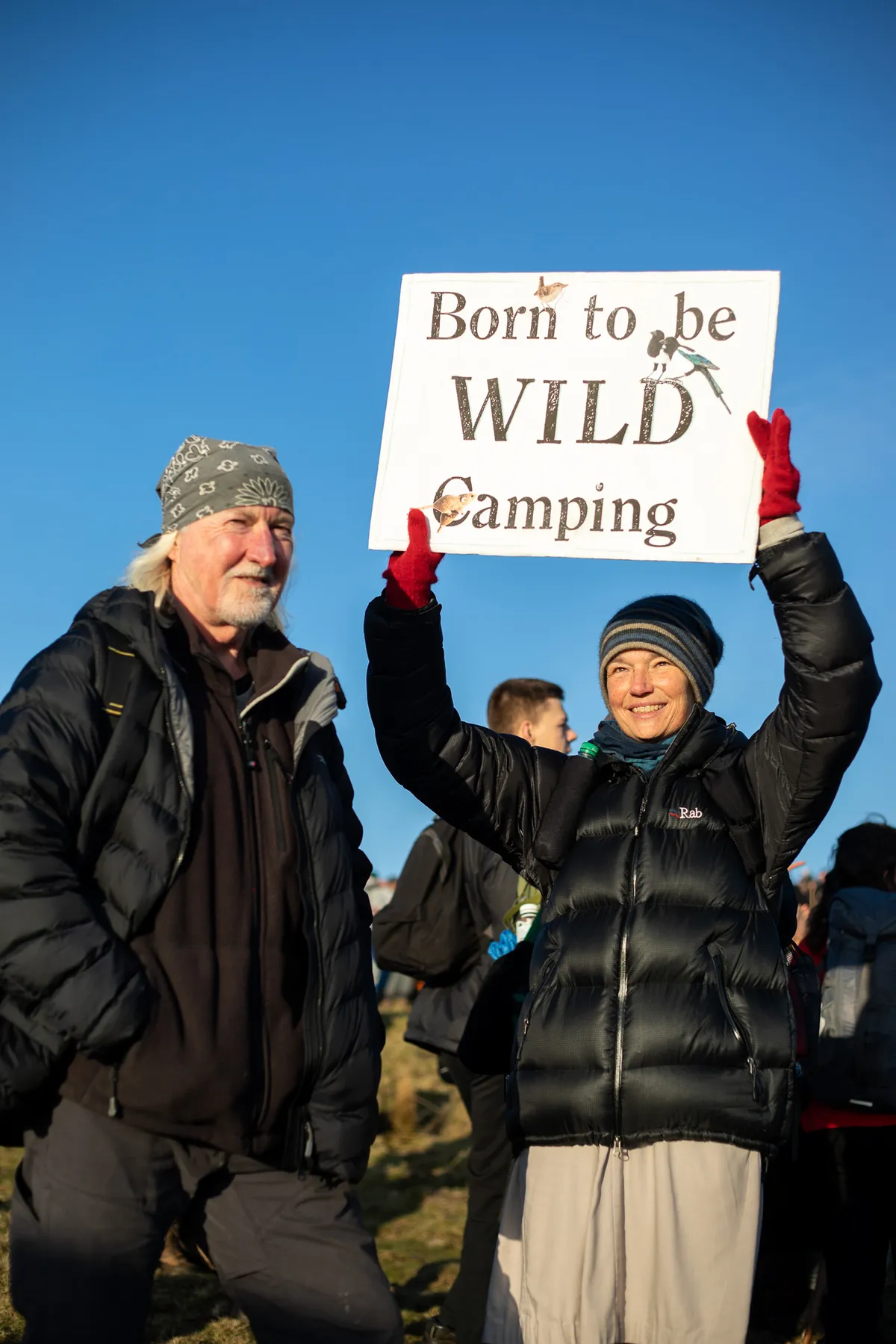 A woman holds a 'Born to be Wild Camping' sign