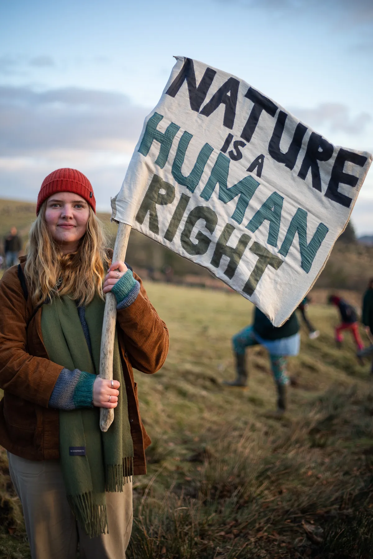 Woman holds 'Nature Is a Human Right' protest sign