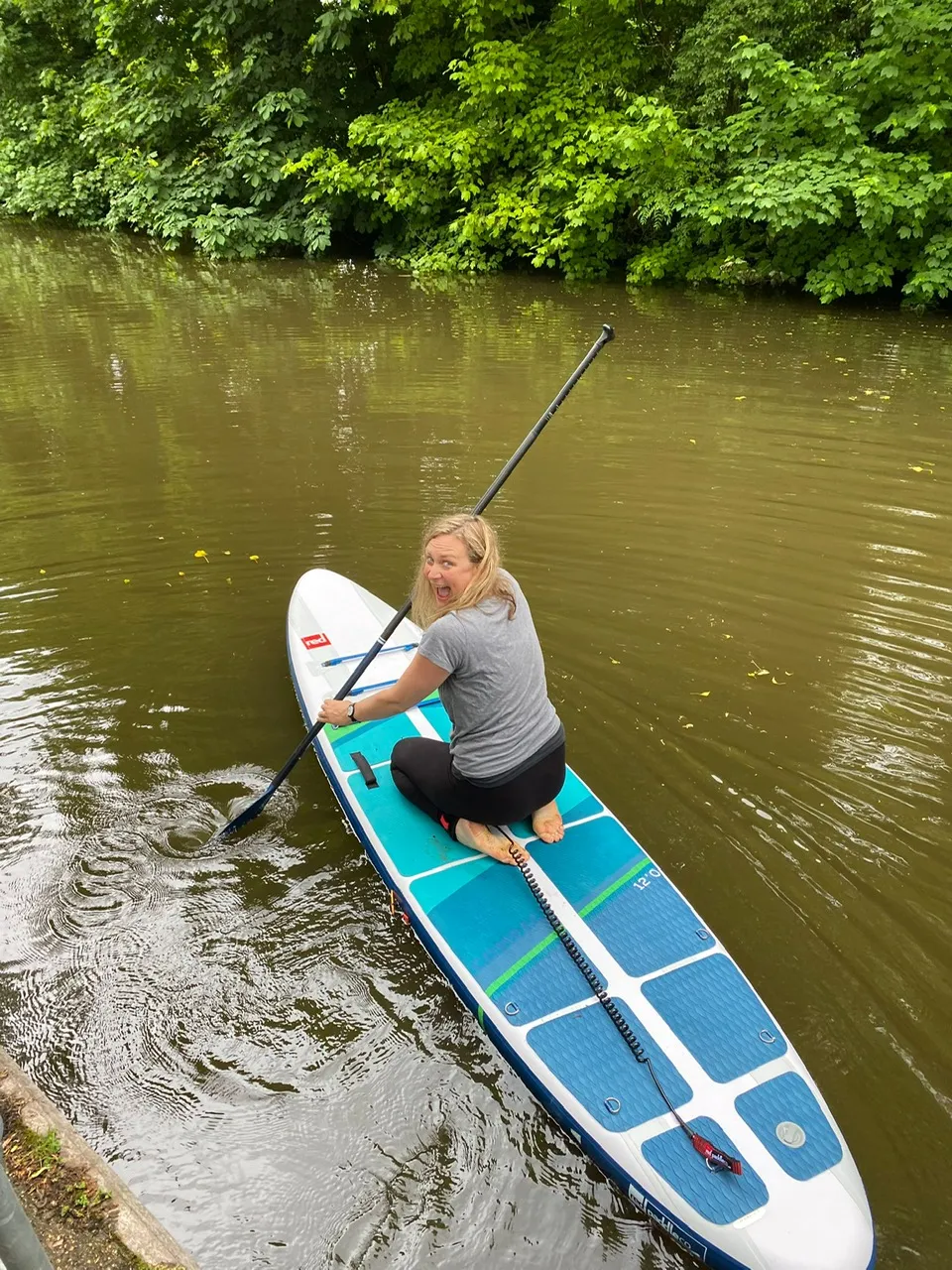 Maria Hodson begins her paddleboarding journey along the Thames with a silly grin looking back at the camera