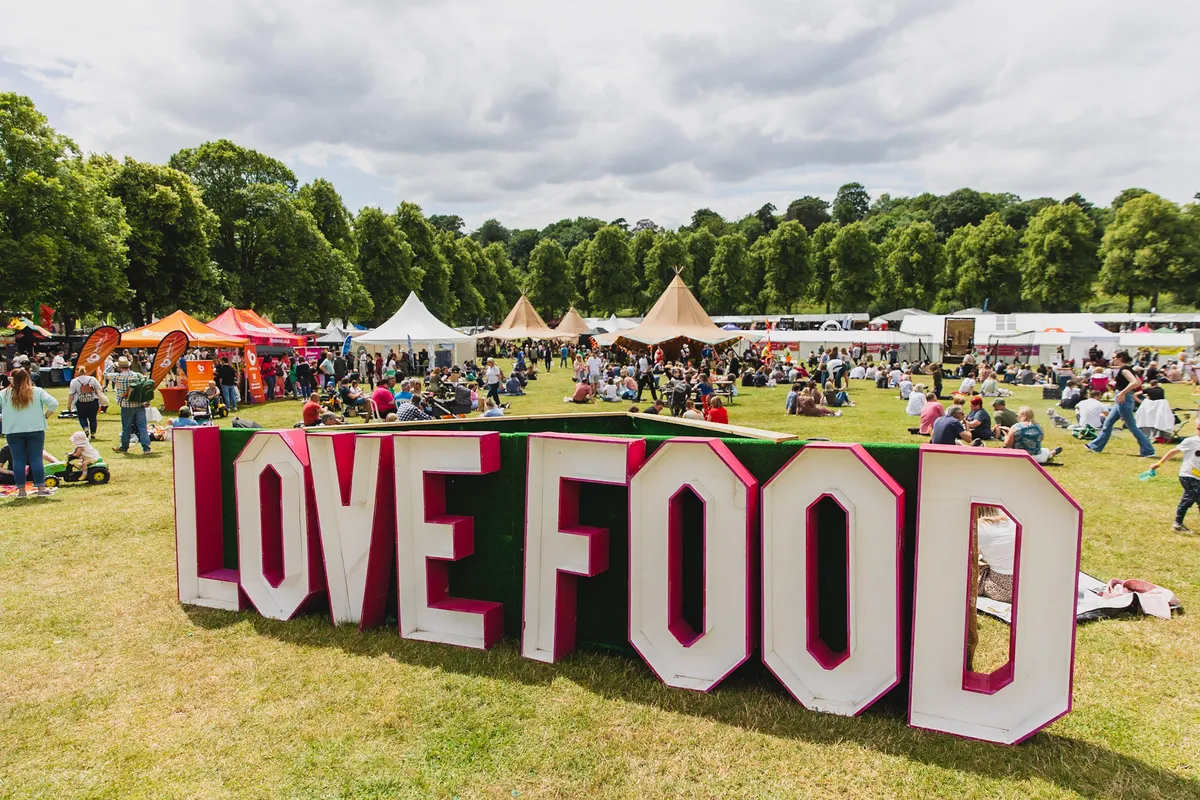 Love food sign at a food festival with stalls in the background