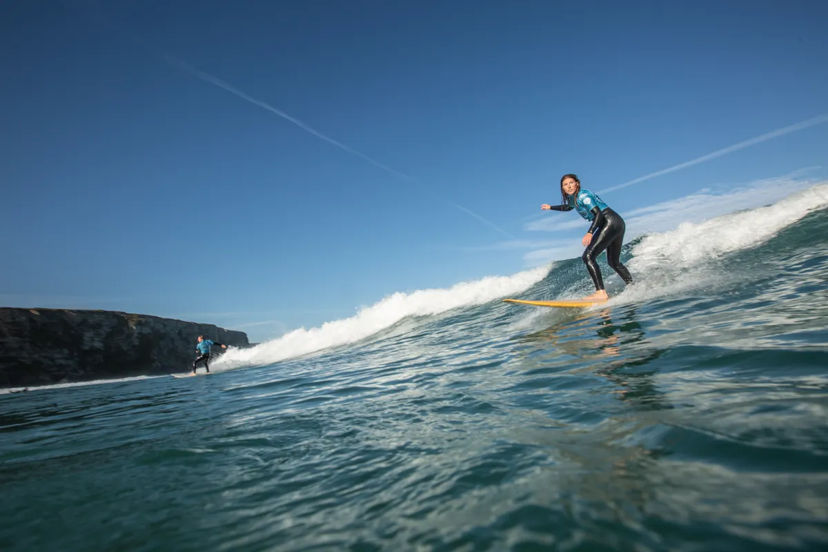 A female surfer rides a wave in Cornwall
