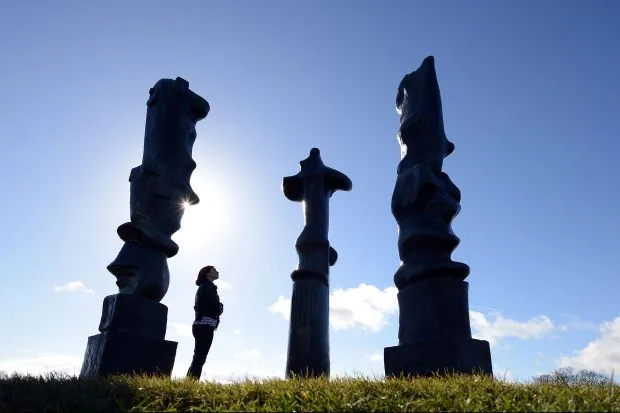 Three towering sculptures surround a woman