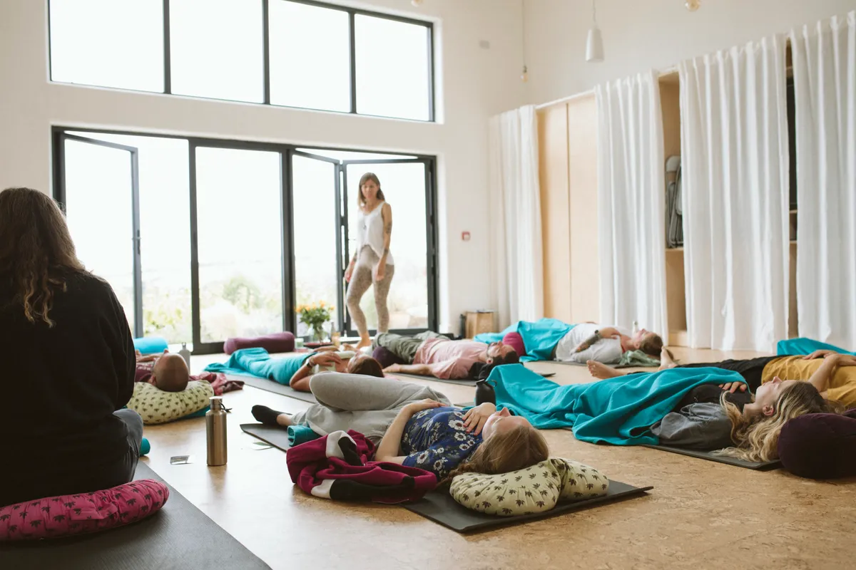 People lie on yoga mats in light room