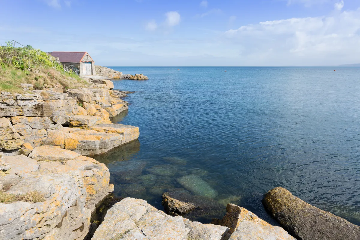 Rocky coastline at Moelfre with old lifeboat station
