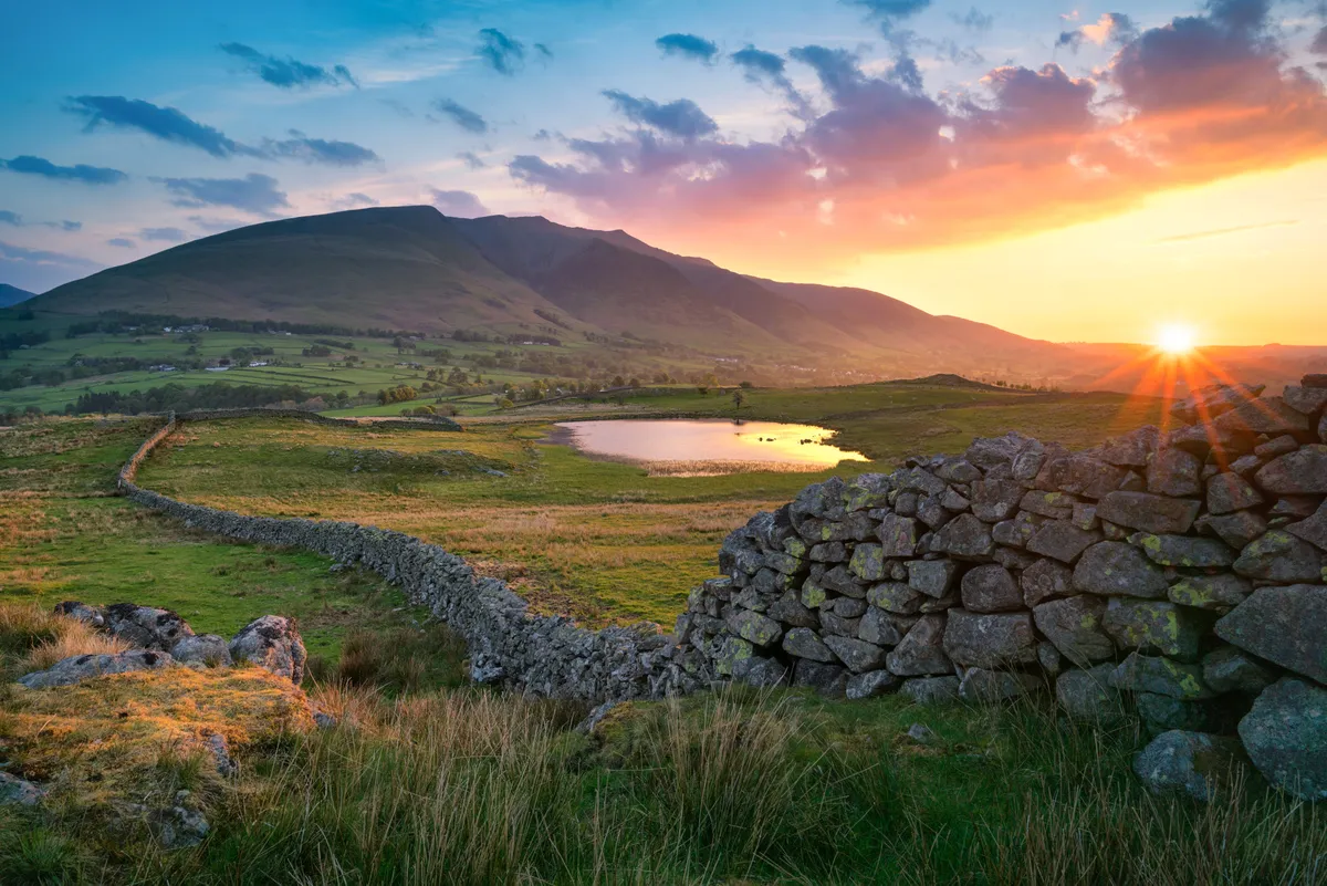 Summer sunrise over Blencathra in the Lake District with traditional stone wall
