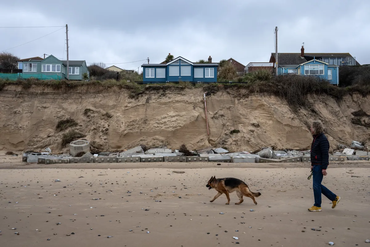 Three bungalows perched on the edge of a rapidly eroding sandstone cliff in March 2023 in Hemsby in Norfolk