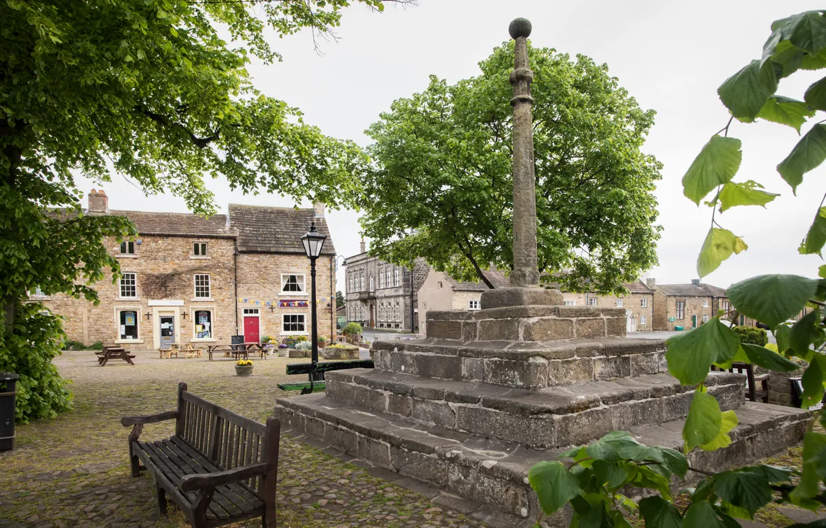 A view of Masham town square showing shops and a monument