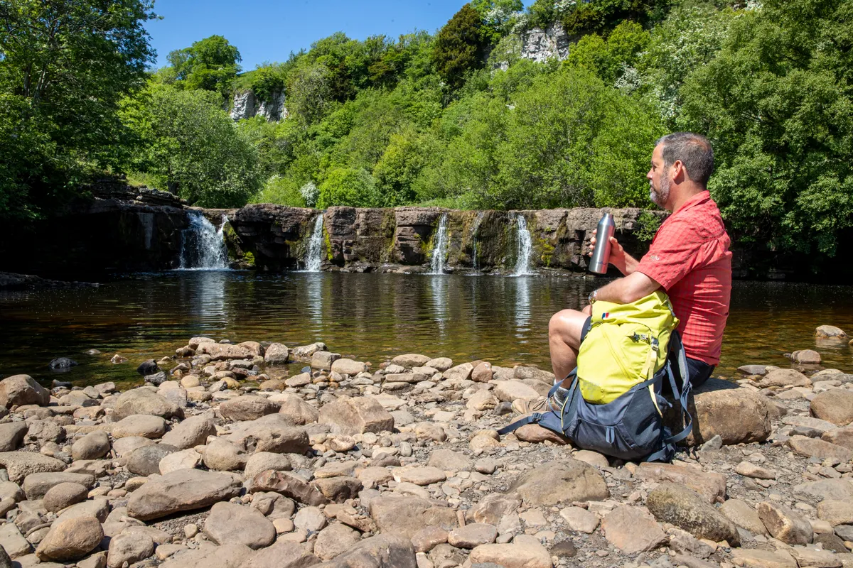 Swaledale waterfalls on a summer day with hiker