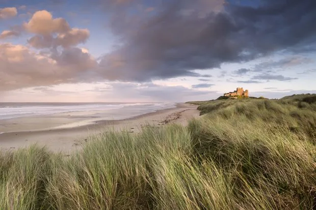 Beautiful landscape and beach and clouds at Bamburgh Castle at sunset