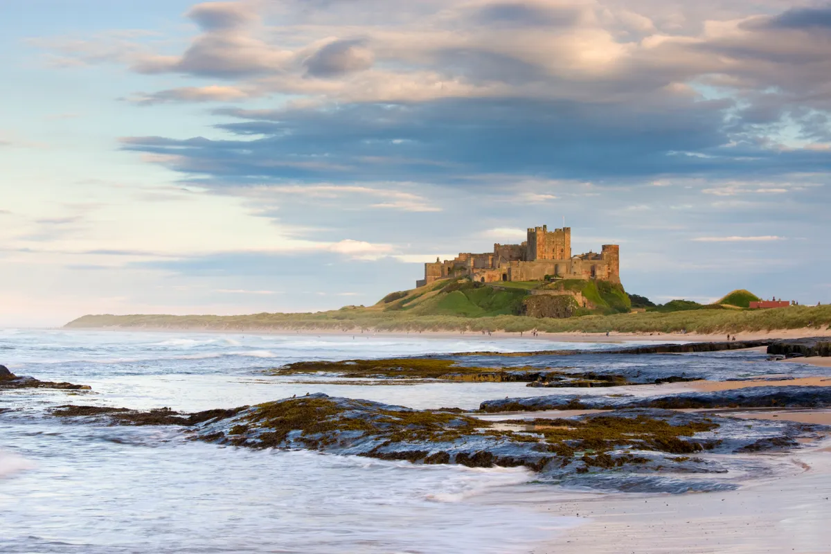 Beautiful landscape and beach and clouds at Bamburgh Castle at sunset