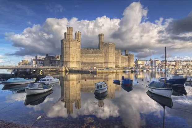 Caernarfon Castle reflecting in water with cloudy sky