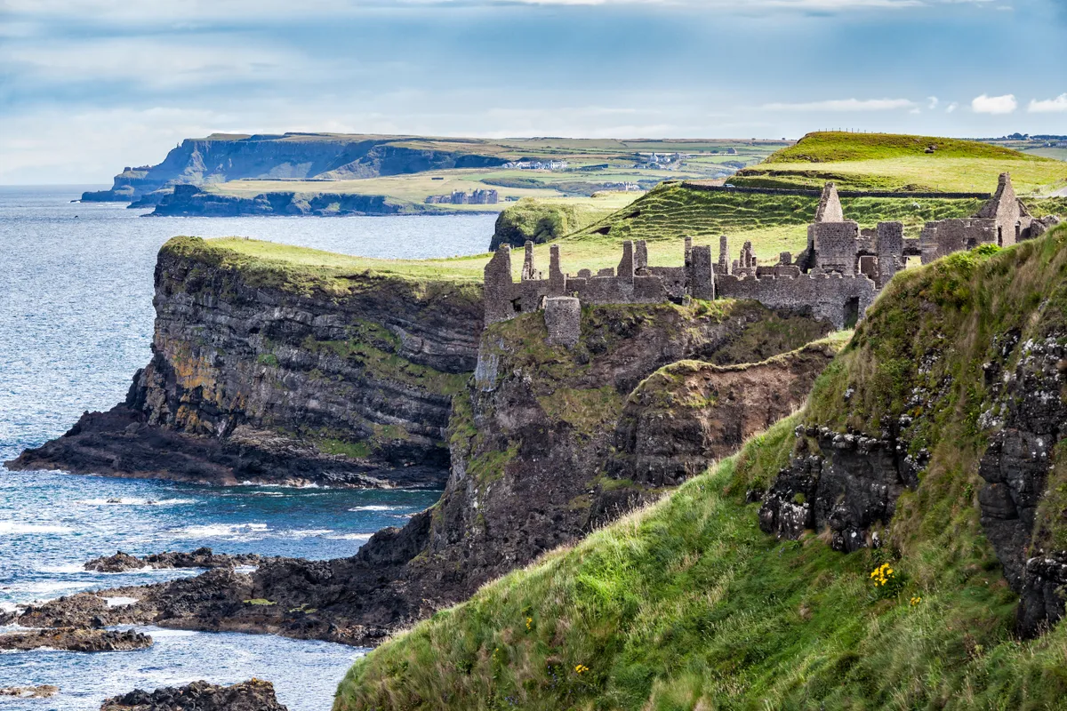 Dunluce Castle on green cliffs with blue sea
