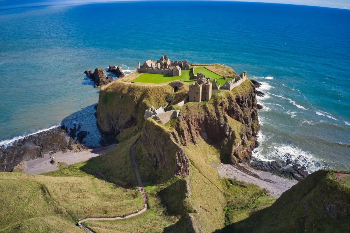 Ruins of Dunnotar Castle with blue sea and green grass