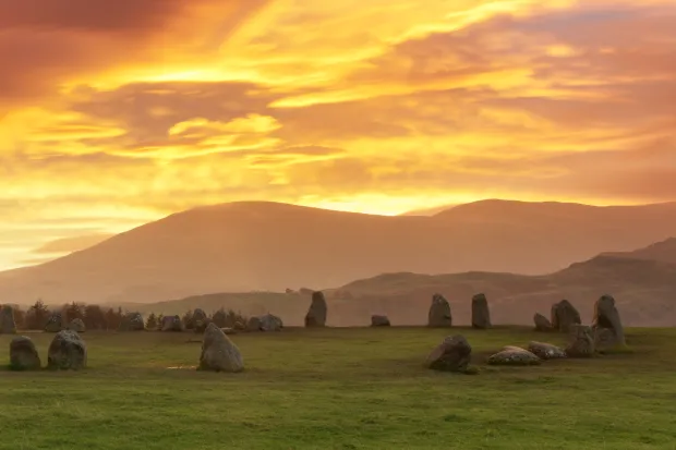 Sunset at Castlerigg Stone Circle with mountains and grass
